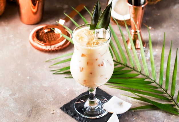 Pina Colada Cocktail sobre fundo bege de areia com frutas tropicais e ferramentas de barra espaço de cópia de conceito de relaxamento de verão