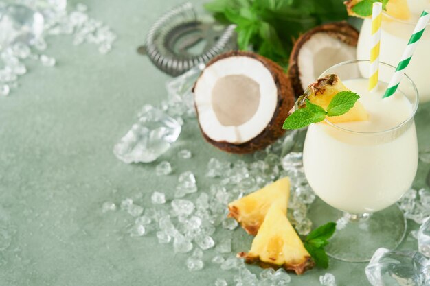 Pina Colada Coquetel caribenho tradicional de suco de abacaxi de rum e creme de coco com frutas tropicais e ferramentas de bar em fundo verde fresco Coquetel tropical de verão e conceito de relaxamento