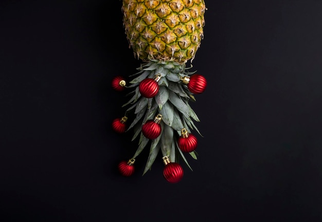 Piña con cordón de Navidad rojo sobre fondo negro Espacio de copia Composición de Navidad