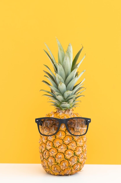 Piña creativa con gafas de sol aisladas en la playa de vacaciones de verano de fondo de color