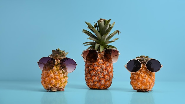 Piña entera con gafas de sol sobre fondo azul Concepto de cóctel y bar de verano