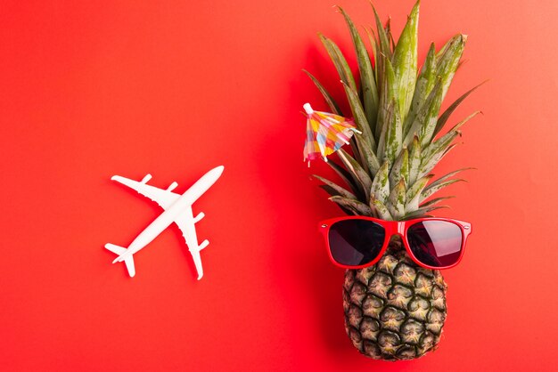 Piña fresca con gafas de sol rojas con modelo de avión