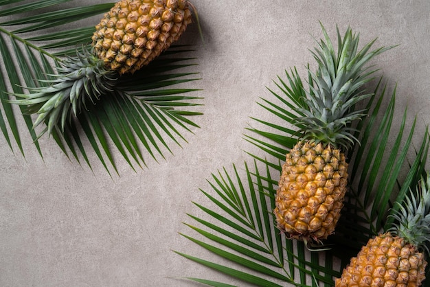 Piña fresca con hojas tropicales sobre fondo gris