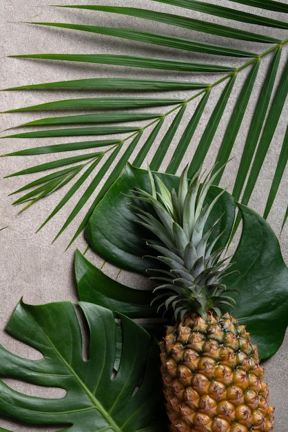 Piña fresca con hojas tropicales sobre fondo gris