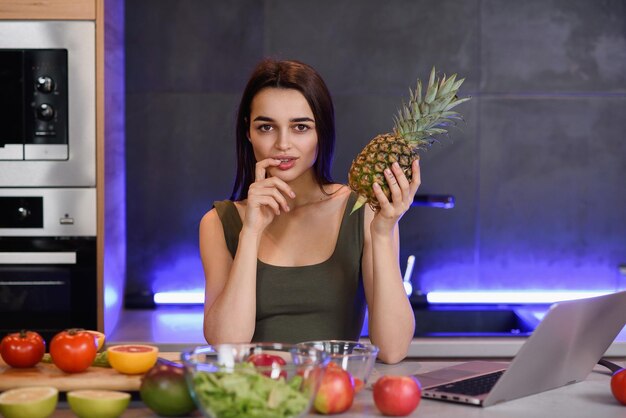 Foto piña fresca en las manos chica en la cocina moderna en casa en su tiempo de fin de semana por la mañana