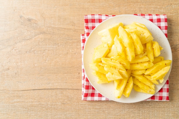 Piña fresca en rodajas en un plato blanco.