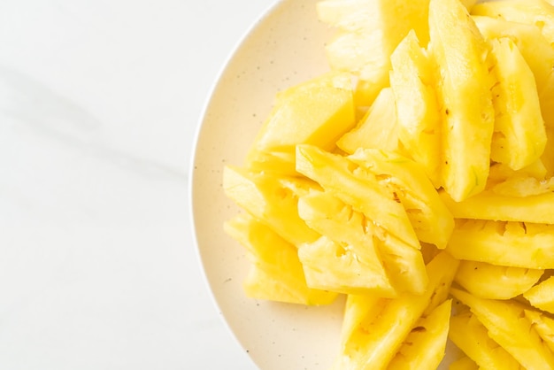 Piña fresca en rodajas en un plato blanco.