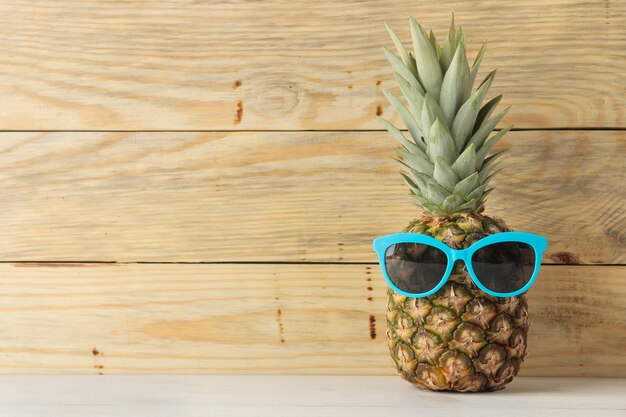 Piña de fruta madura en gafas de sol sobre una mesa de madera natural. verano.