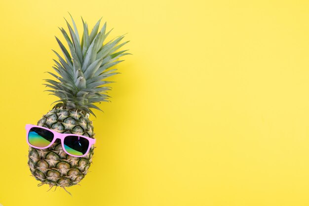 Piña con las gafas de sol rosadas para las vacaciones de verano y el concepto de las vacaciones.