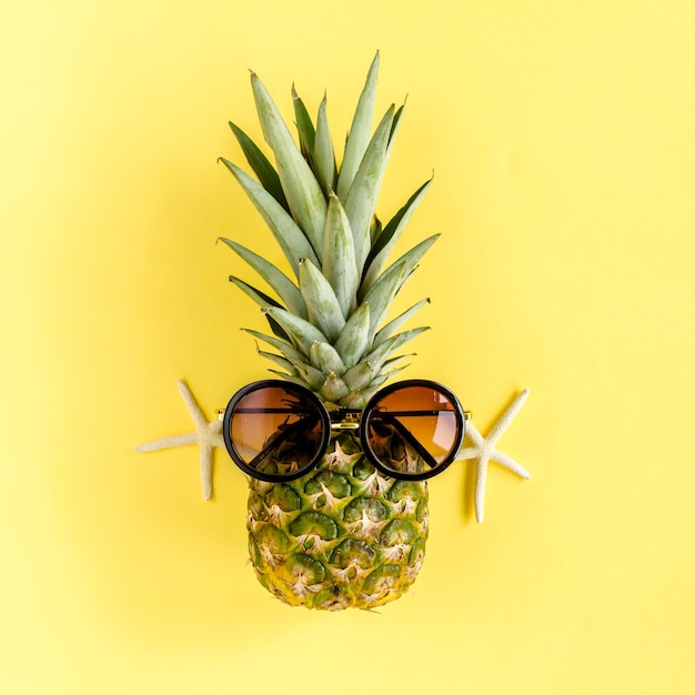 Piña hipster en gafas de sol sobre fondo amarillo fondo de verano endecha plana