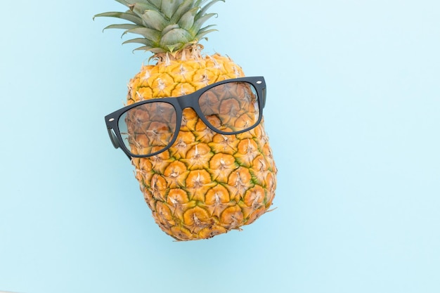 Piña hipster con gafas de sol sobre un fondo azul.