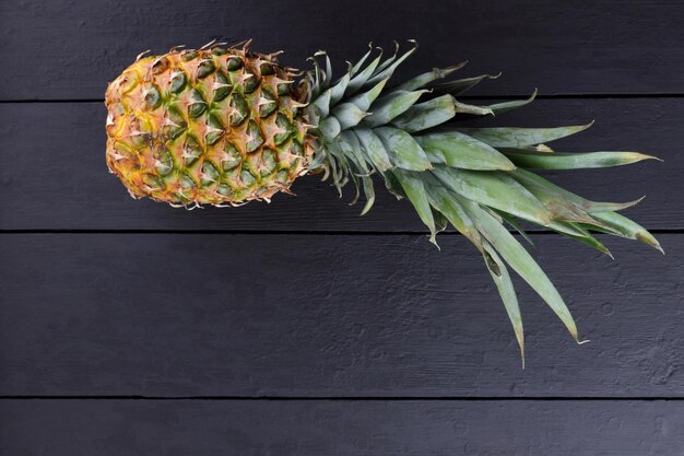 Piña con hojas sobre tablas de madera negras Ananas sobre fondo negro Comida vegetariana Espacio de copia