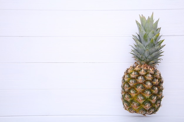 Piña madura sobre un fondo blanco de madera con espacio de copia