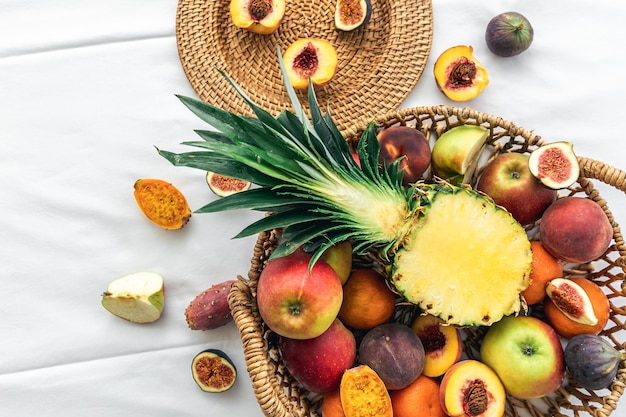 Piña y otras frutas exóticas en una cesta en una vista superior de fondo blanco