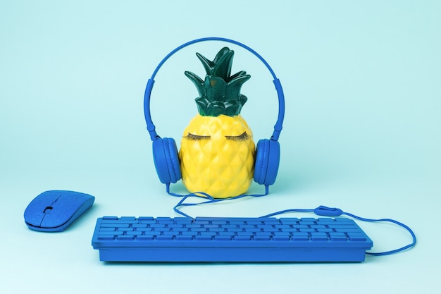 Piña usando audífonos con teclado y mouse