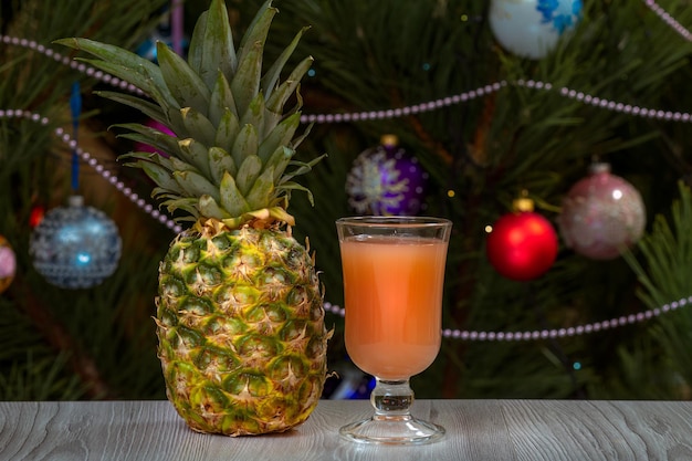 Piña un vaso de jugo y un abeto con adornos navideños