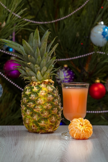 Piña un vaso de jugo y un abeto con adornos navideños