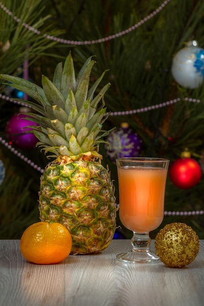 Piña un vaso de jugo y un abeto con adornos navideños