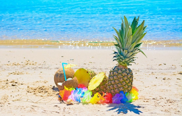 Piñas y cocos a la orilla de una playa tropical