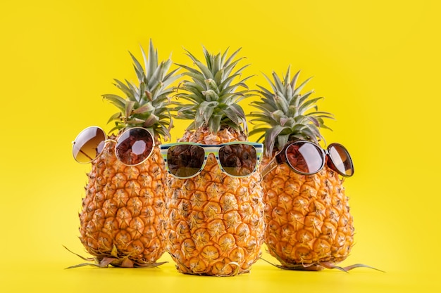 Piñas creativas con gafas de sol aisladas sobre fondo amarillo, patrón de diseño de idea de playa de vacaciones de verano, espacio de copia, de cerca, en blanco para texto