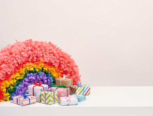 Pinata de arco iris y regalos coloridos envueltos en papel hermoso con arcos de regalo Copiar espacio para el texto