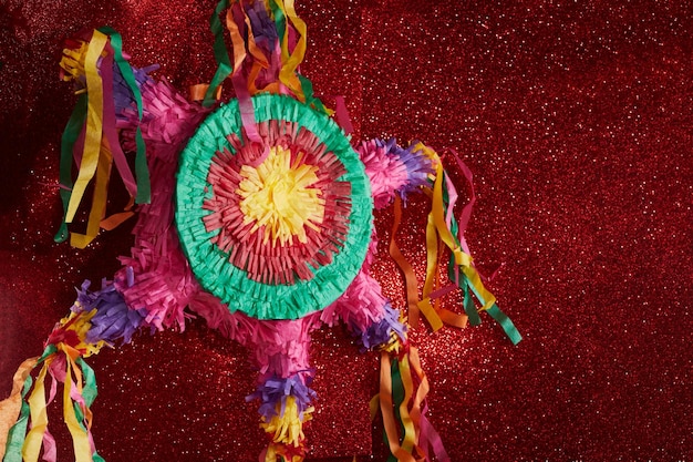 Piñata mexicana utilizada en posadas y cumpleaños sobre fondo rojo.