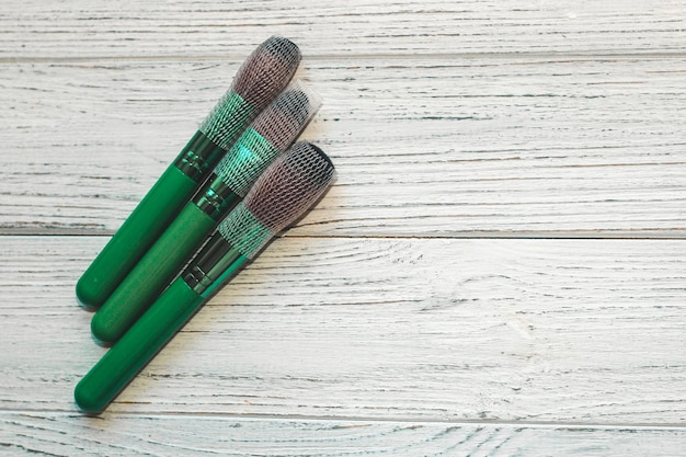 Pincéis de maquiagem verde em uma mesa de madeira