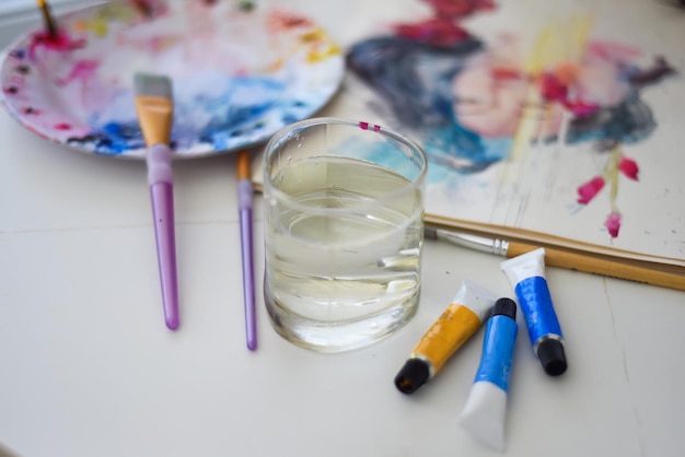 Foto pincéis e água sobre uma mesa com uma paleta de arte