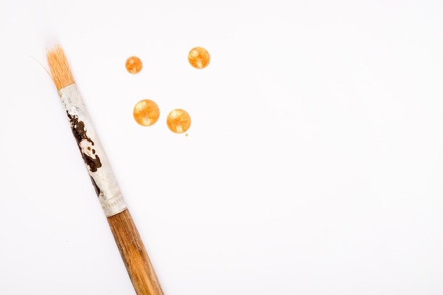 Foto pincéis e gotas de acrílico sobre fundo branco tinta dourada e pincel profissional em branco