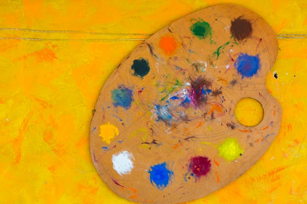 Pincéis e paleta colorida de pintores de cores de óleo abstratas em fundo amarelo