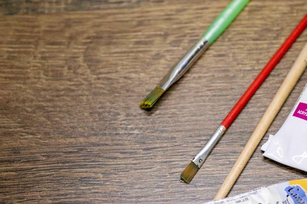 Pincéis e tintas estão em uma mesa de madeira