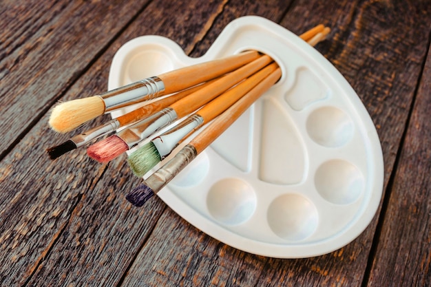 Pincéis para pintura e paleta sobre uma velha mesa de madeira