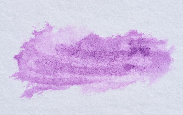 Pincel de acuarela de pintura violeta en un papel blanco