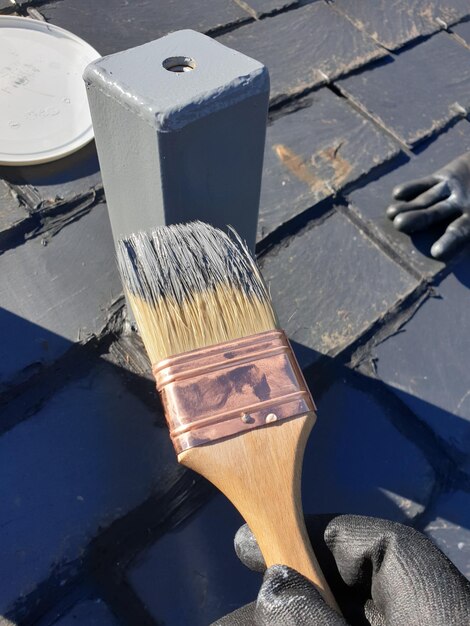 Pincel de homem pintando um poste de metal cinza