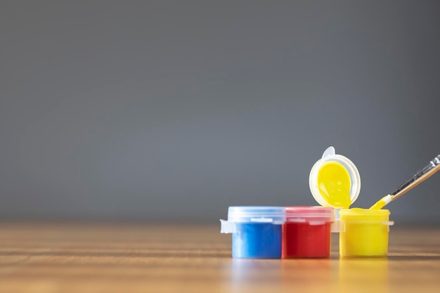 Pincel de pintura de artista com tinta colorida na mesa de madeira fundo cinza cópia espaço azul vermelho amarelo