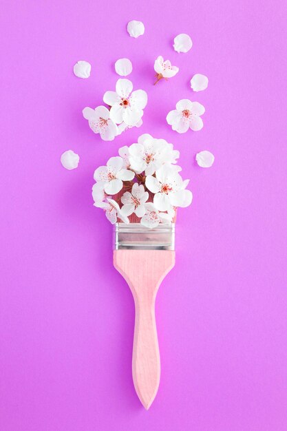 Pincel con flores blancas sobre fondo rosa. Composición de flores creativas Vista superior.