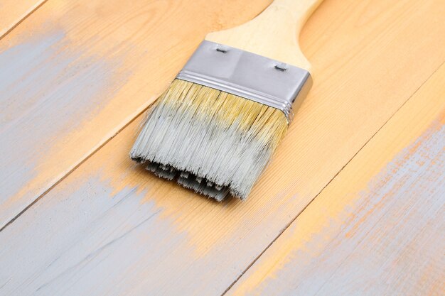 Pincel con lata de pintura sobre tablas de madera en un pincel gris