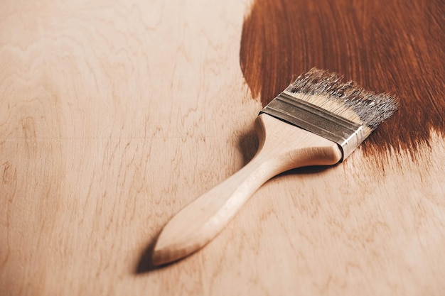 Pincel con mango de madera y cerdas naturales sobre fondo de tablones de madera pintados de marrón