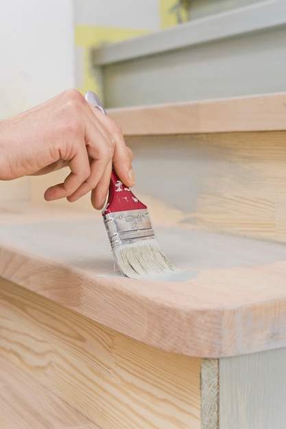 Pincel en mano, aplicando pintura a una superficie de madera durante la reparación