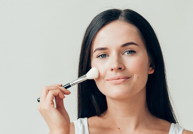 Pincel maquillaje mujer cara piel sana maquillaje natural en polvo. Tiro del estudio.