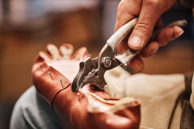 Foto pincel metálico na mão de um sapateiro masculino fixando a parte superior da bota na sola