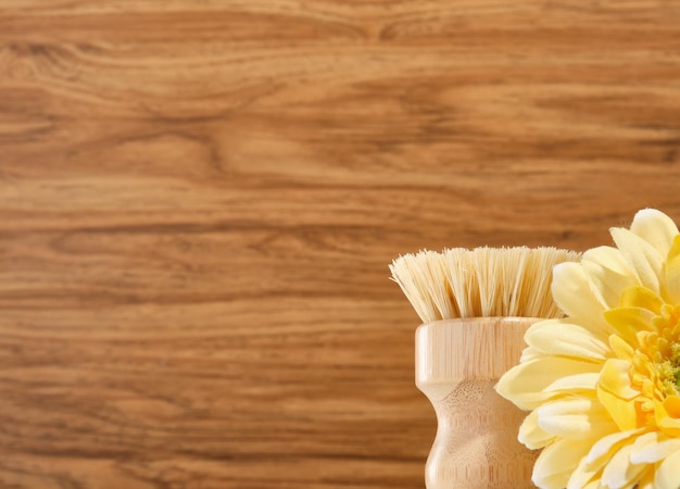 Pincel redondo natural ecológico y flor amarilla sobre un fondo de madera Copiar espacio para el texto