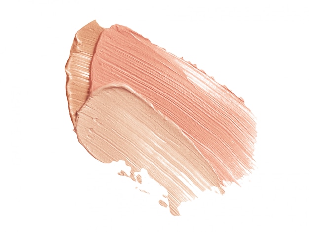 Las pinceladas de corrector beige y rosa aisladas en blanco