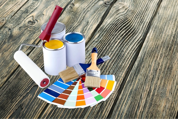 Pinceles y botes de pintura para reparar sobre fondo de madera