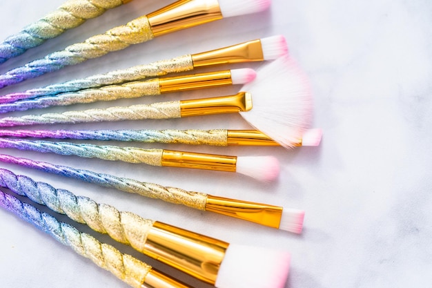 Pinceles de maquillaje de color unicornio sobre un fondo de mármol.