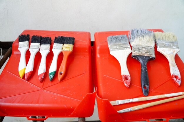 Pinceles en un recipiente de plástico rojo en el fondo de la pared blanca