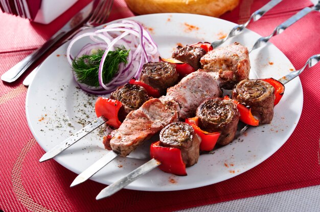 Los pinchos del cerdo y de las verduras asaron a la parrilla, concepto sano de la comida, foco selectivo en fondo de madera. Comida del este.