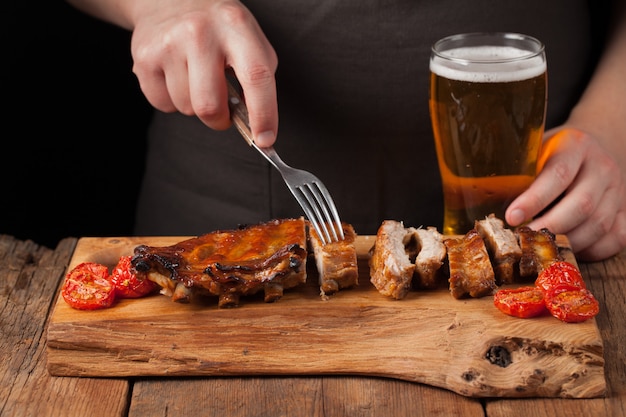 Pinchos de cocinero de hombre con un tenedor listo para comer costillas de cerdo.