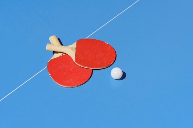 Ping-Pong-Tisch-Hintergrund Tennisschläger und ein Ball auf einem blauen Sporttisch