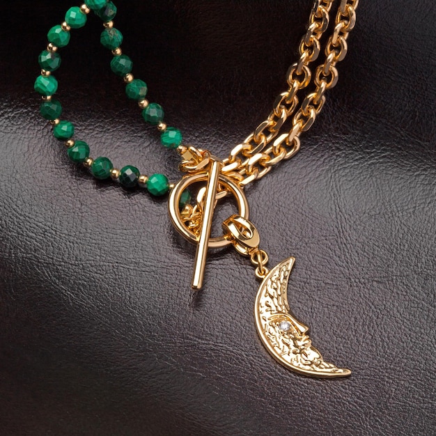 Pingente feminino em forma de lua dourada com corrente dourada e malaquita verde xDneklace em fundo de couro marrom Captura de fundo